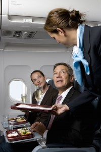 Business people on a plane being served meals and champagne